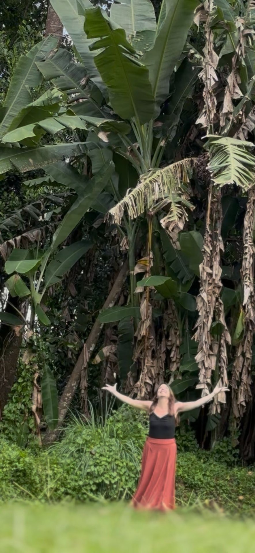 Elaine Palmer standing with her arms outstretched in the jungle